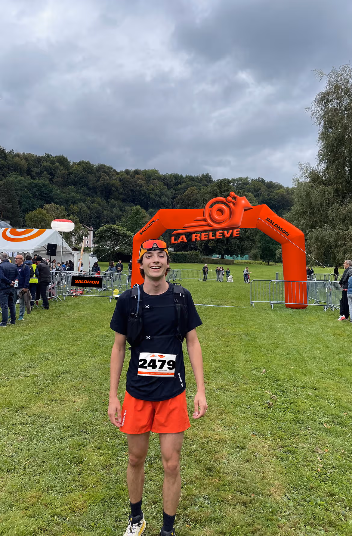 Jeune coureur portant un dossard lors d’un événement La Relève devant une arche de départ orange