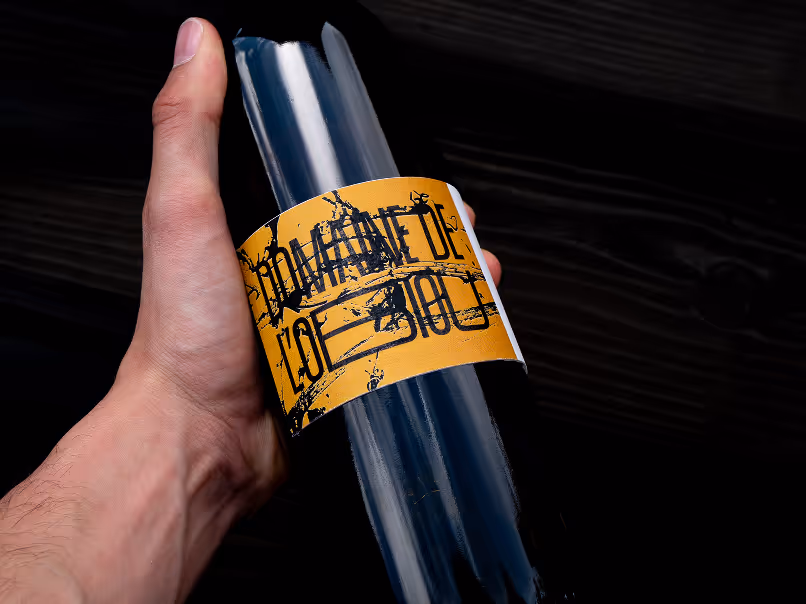 Main tenant une bouteille en verre foncé avec une étiquette jaune.